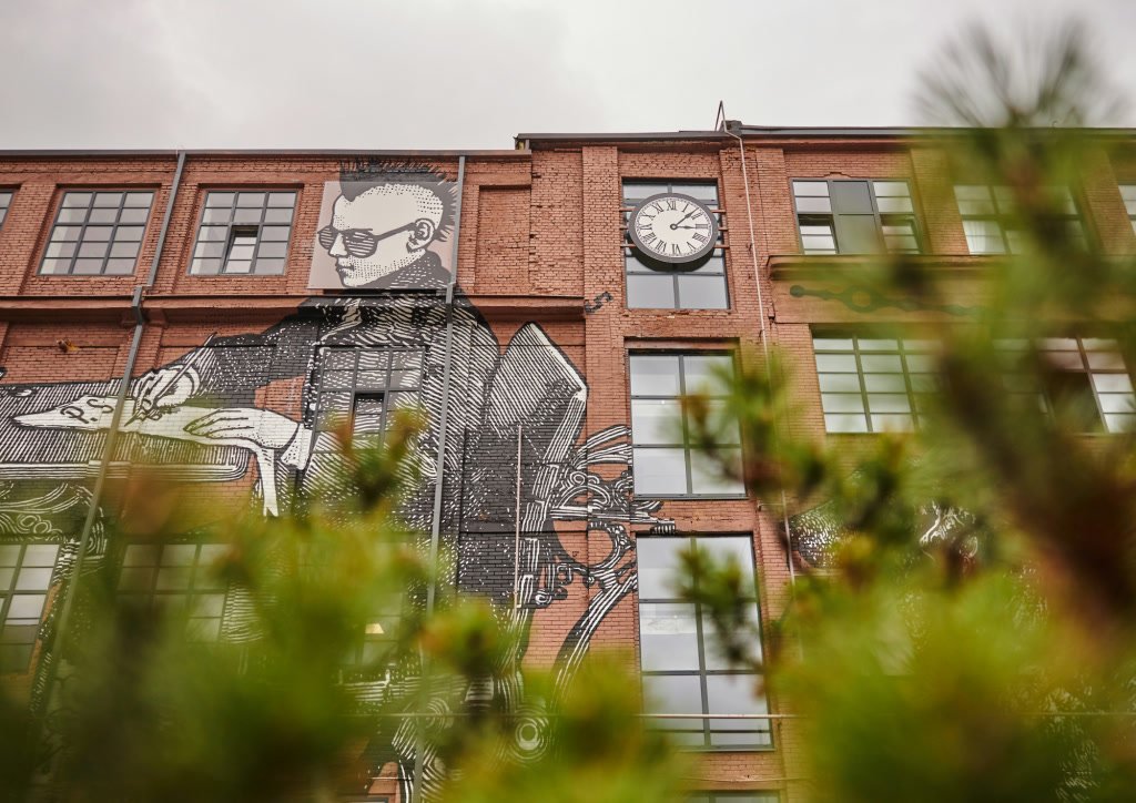 Drobės fabriko plytų fasadas su muralu ir laikrodžiu